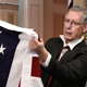 Through a series of pulses along its stripes, an American flag conveys to Senate Majority Leader Mitch McConnell the means by which Medicaid can cover every American all the way back to before the invention of time.